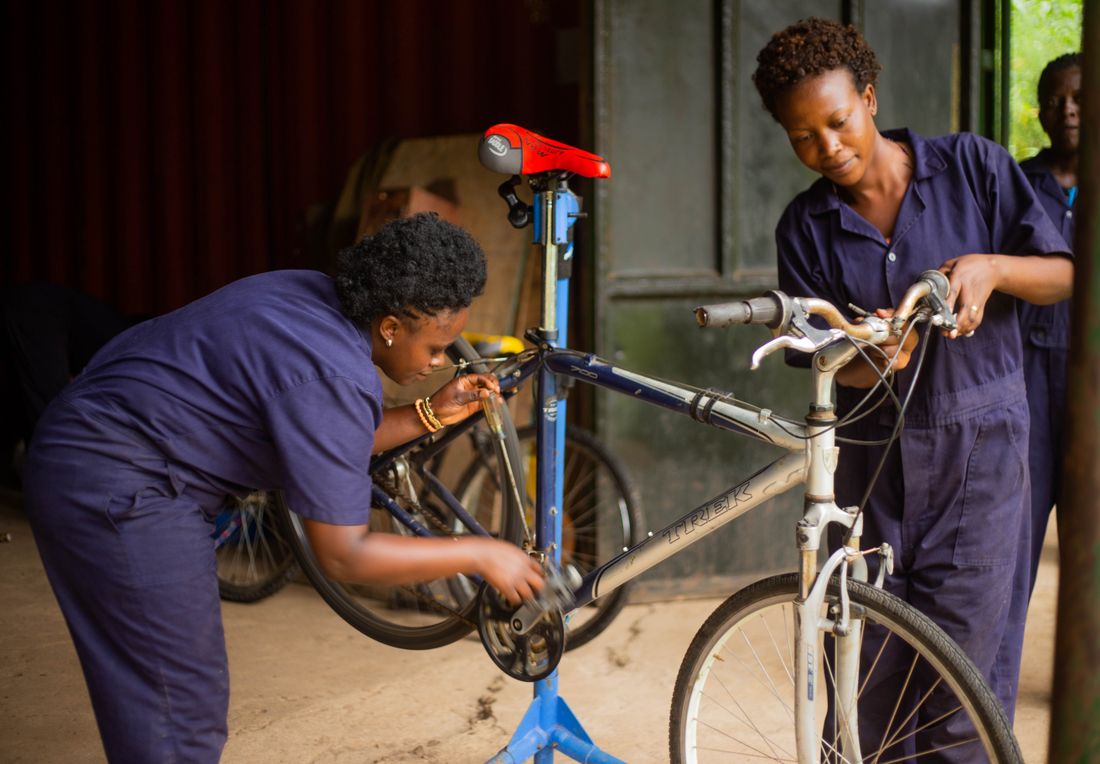 Two mechanics servicing a bicycle on a work stand